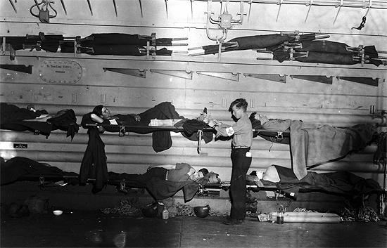 Navy medical corpsman caring for wounded soldiers in an LST tank bay, converted to a hospital